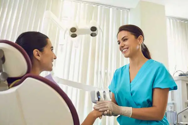 Smiling oral surgeon holding her female patients hands and discussing dental crown procedure at San Francisco Dental Arts in San Francisco, CA