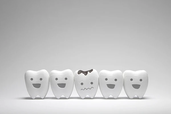 Row of five animated teeth, all smiling except for the middle tooth which frowns, due to tooth decay.