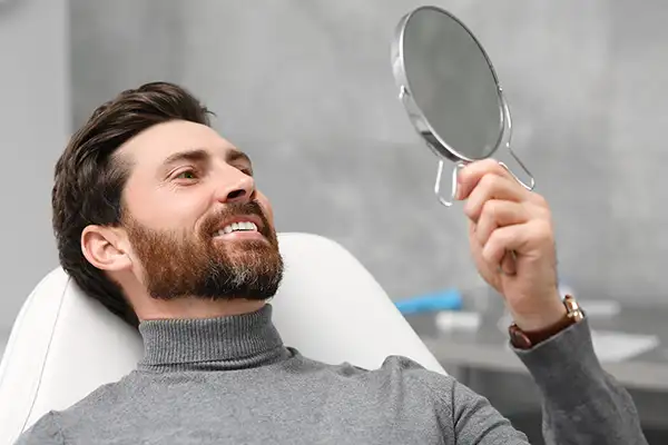 Smiling dental patient leaning back in exam chair and looking up into mirror at his new at San Francisco Dental Arts in San Francisco, CA Smiling dental patient leaning back in exam chair and looking up into mirror at his new at San Francisco Dental Arts in San Francisco, CA