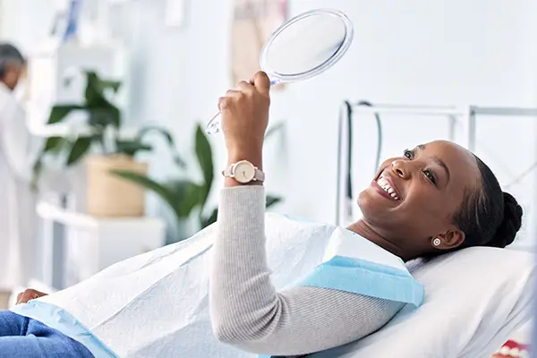 Smiling dental patient looking into mirror after wisdom teeth removal at San Francisco Dental Arts in San Francisco, CA Smiling dental patient looking into mirror after wisdom teeth removal at San Francisco Dental Arts in San Francisco, CA