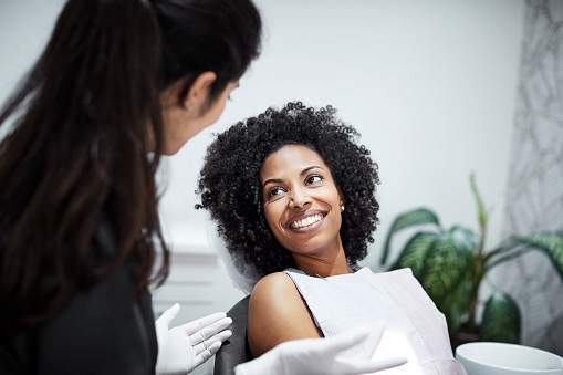 Beautiful Black woman talking to dentist during dental exam 
