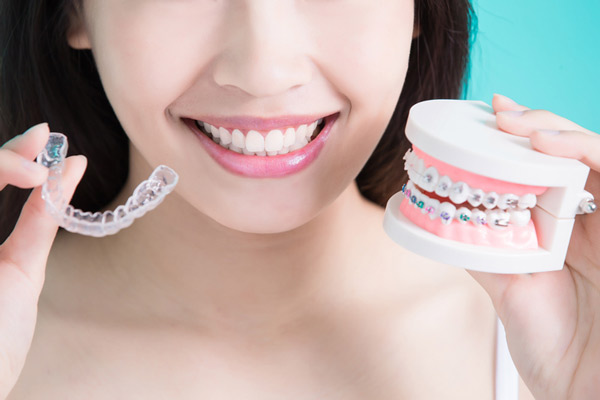 Close up of young woman holding clear aligner and braces demo from San Francisco Dental Arts in San Francisco, CA