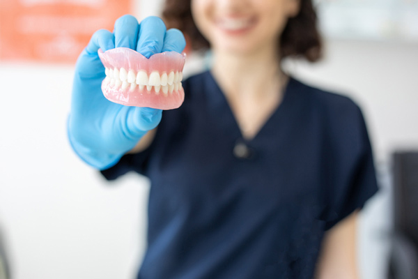 Woman holding a set of dentures from San Francisco Dental Arts in San Francisco, CA