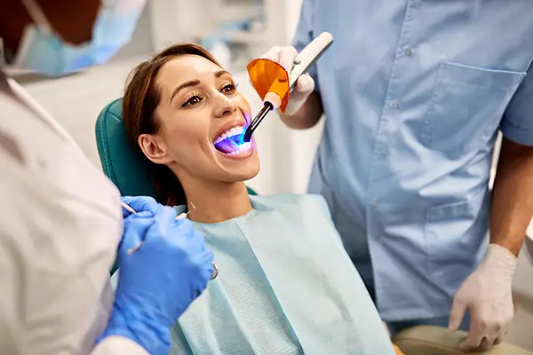 Dentist and assistant performing a dental bonding procedure on a female patientSan Francisco, CA